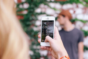 Smartphone photographing young man by brick wall