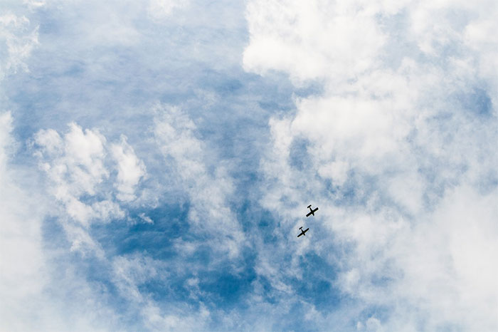 Two small airplanes against cloudy blue sky