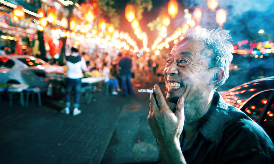 Man laughing while smoking at crowded night market