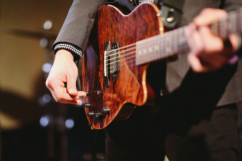 Close-up of hands tuning electric guitar