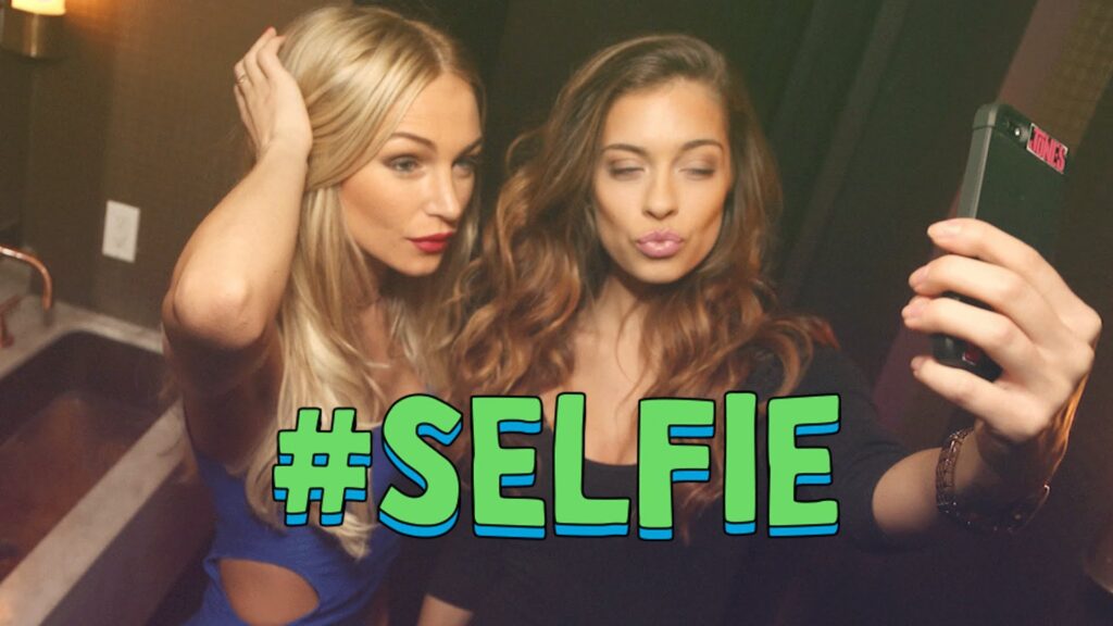 Two women taking smartphone selfie with hashtag overlay