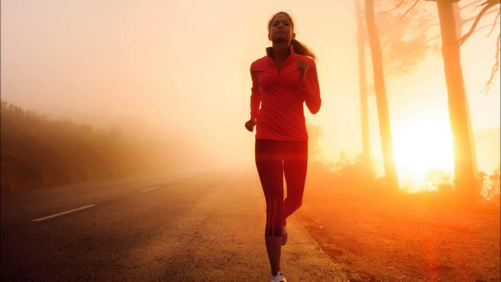 Woman running on foggy sunrise road