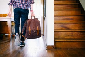 Person carrying brown backpack indoors near stairs