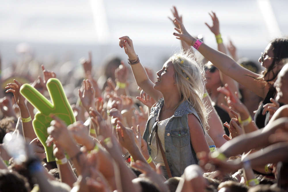 Young woman reaching up at outdoor concert